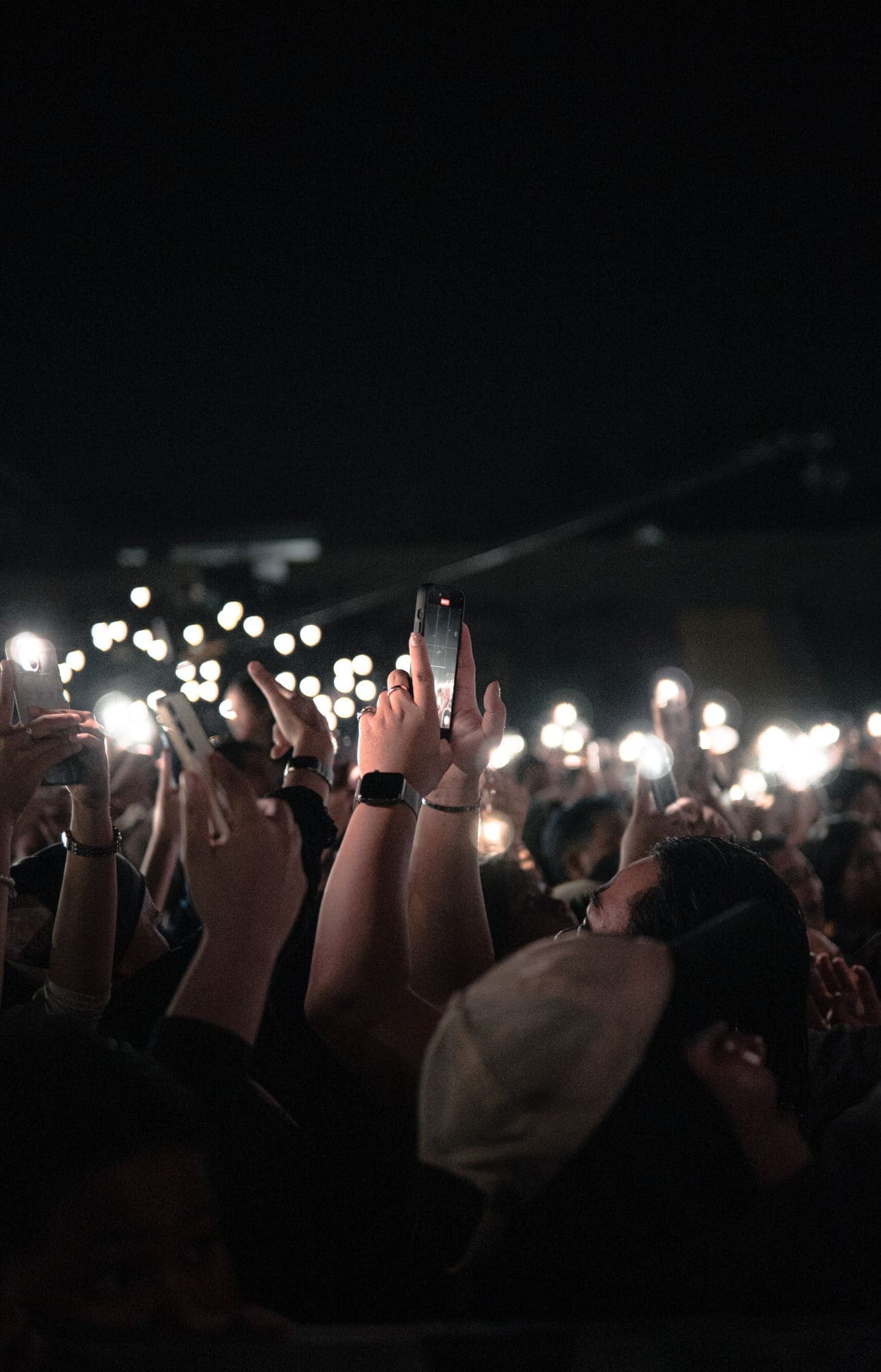 A crowd holding up glowing phone lights at a night event