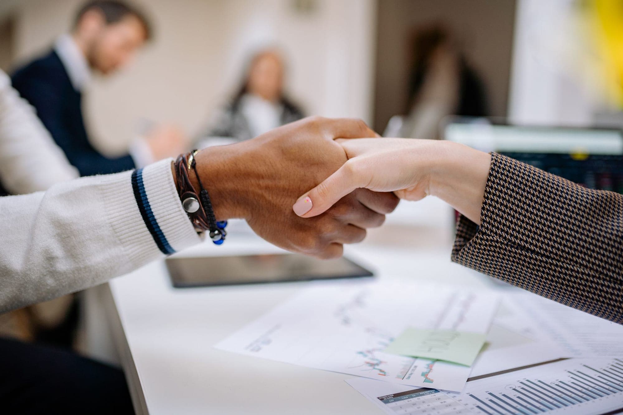 Two people shaking hands over documents