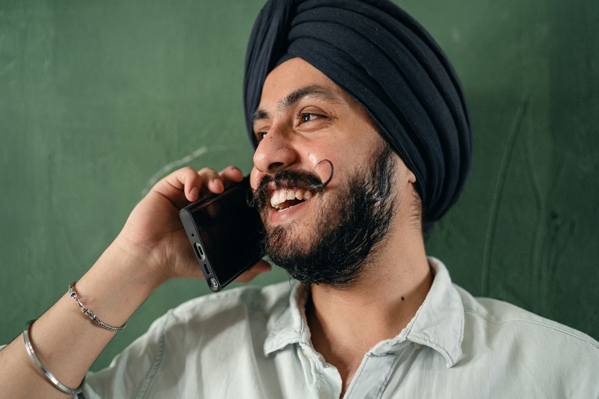 A smiling man in a turban talking on his phone