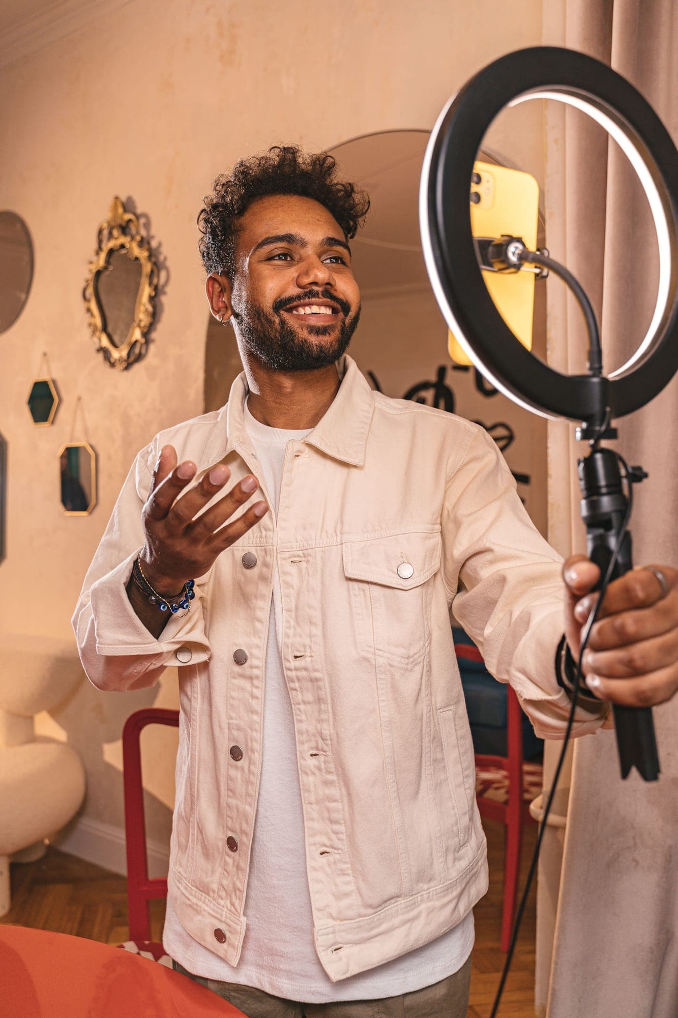 A smiling man talking to camera beside a ring light