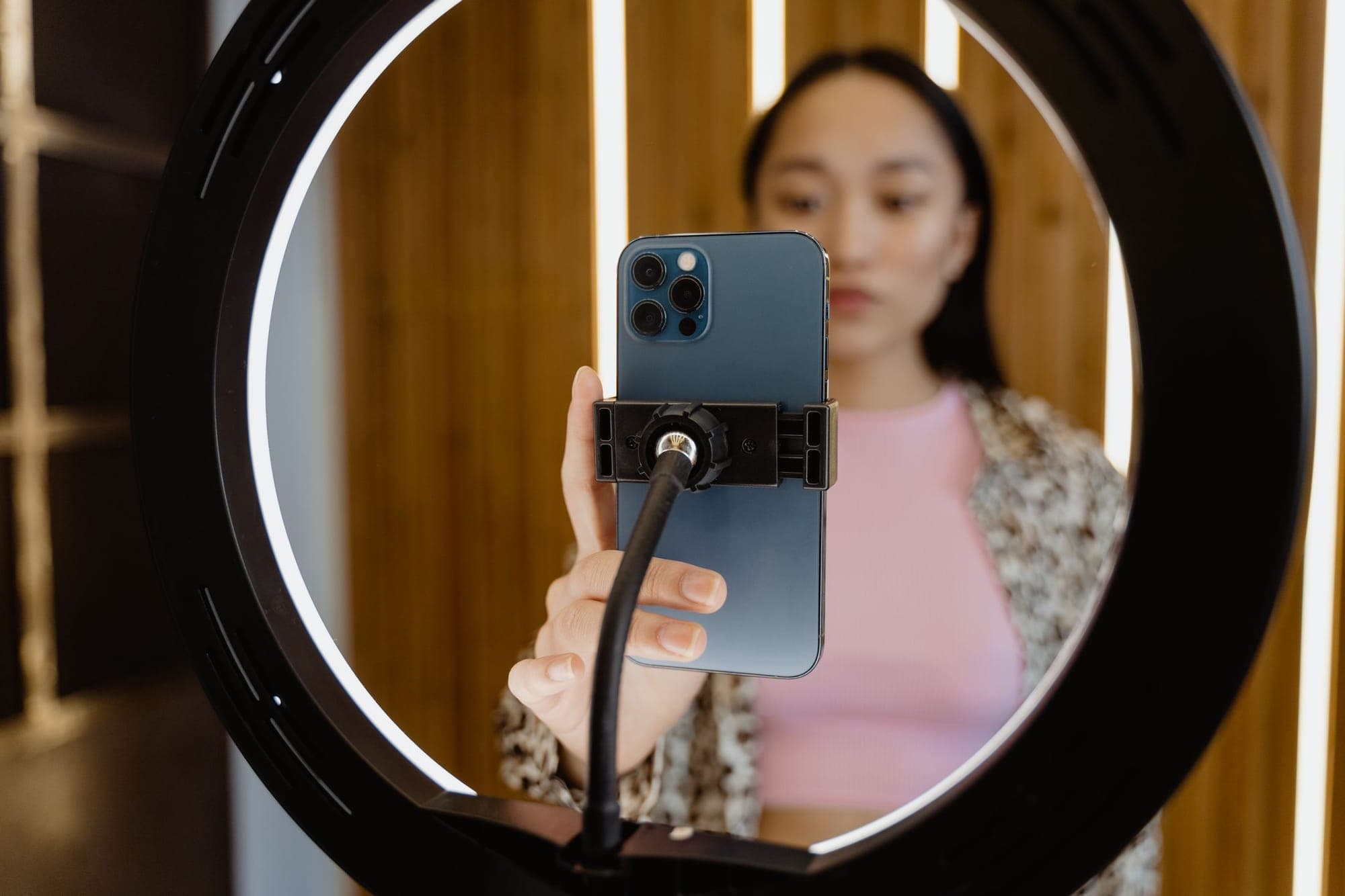 A woman framed by a ring light holding a smartphone