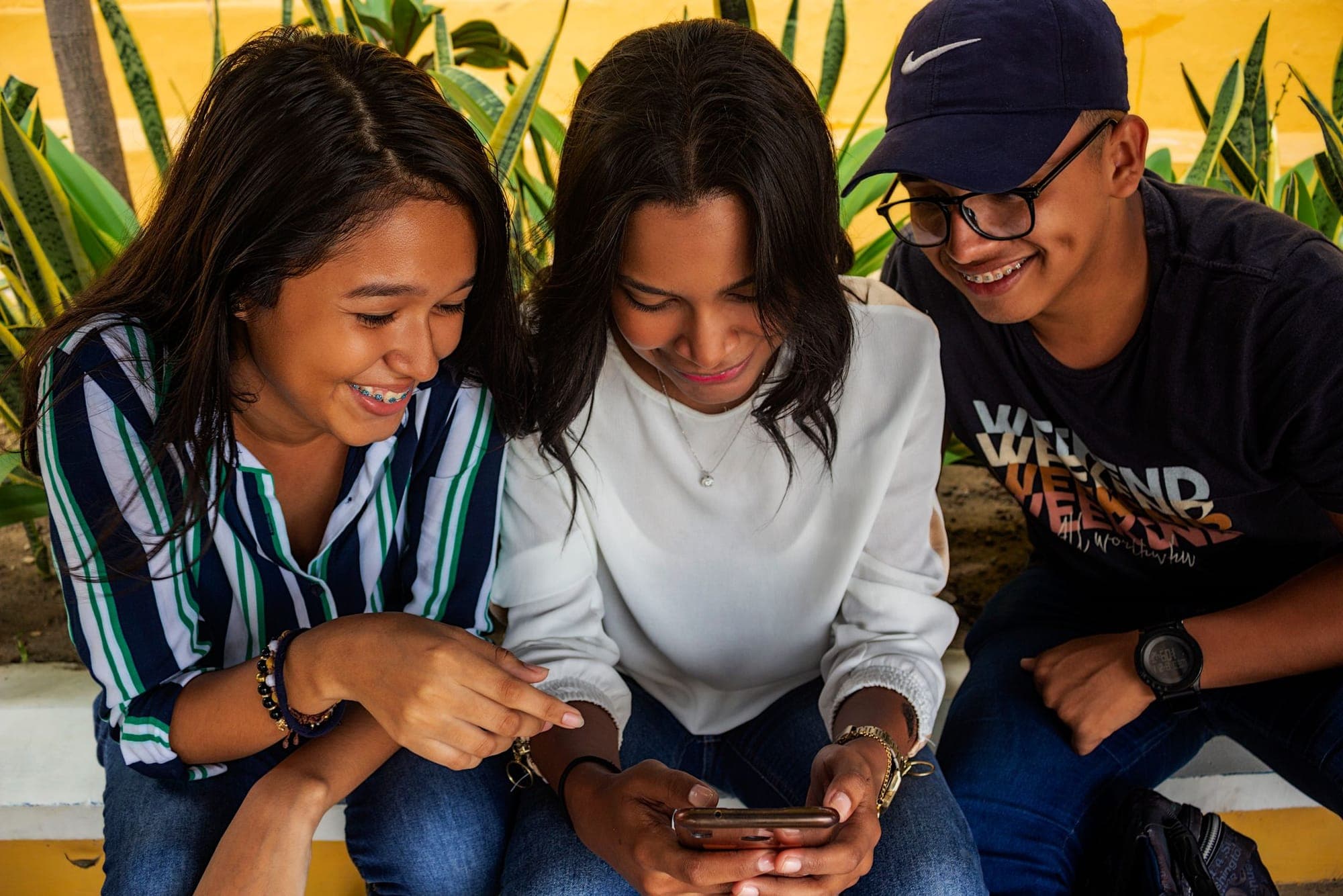 Three friends laughing together over a smartphone