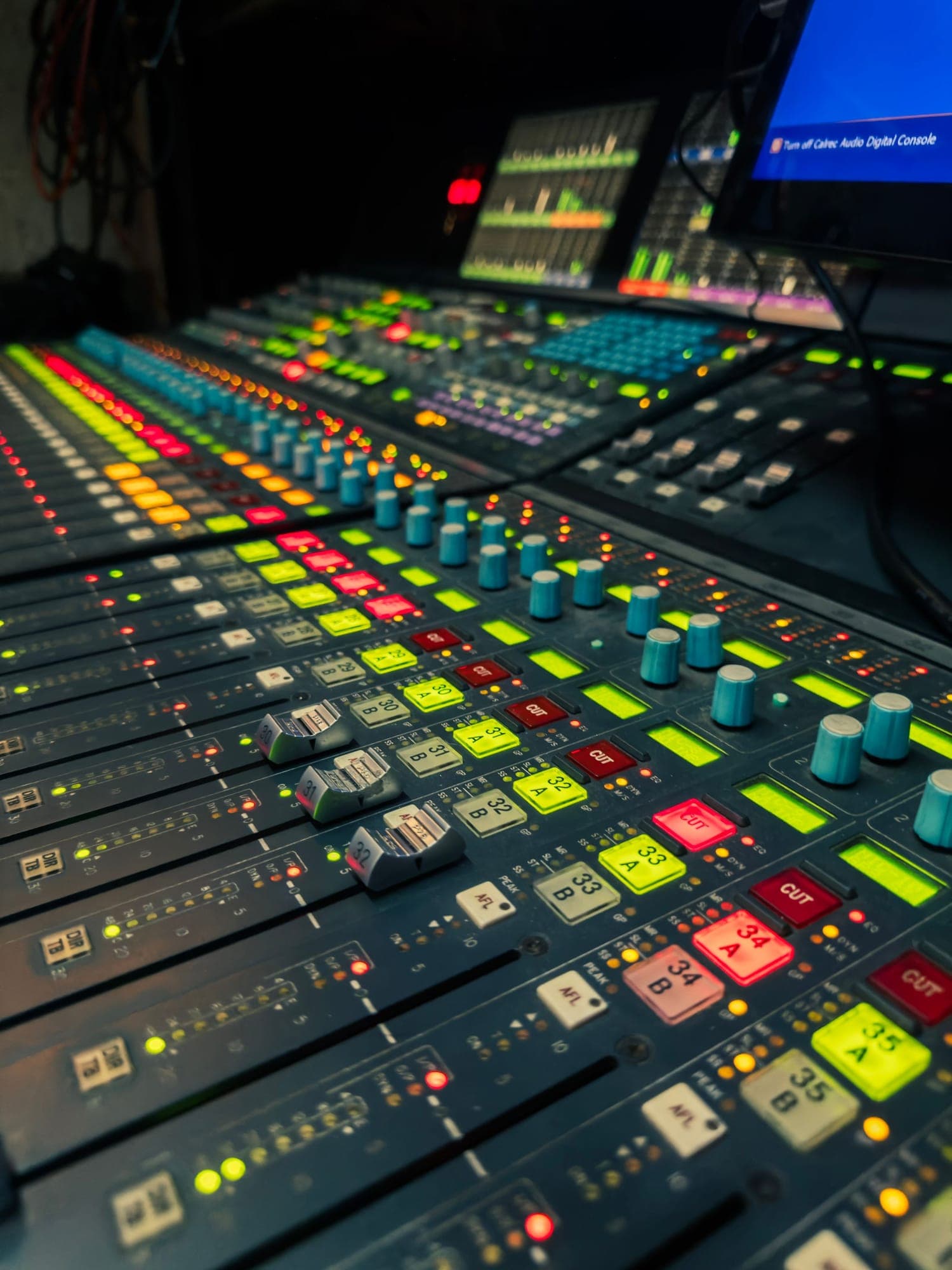 A colourful audio mixing console in a dark studio
