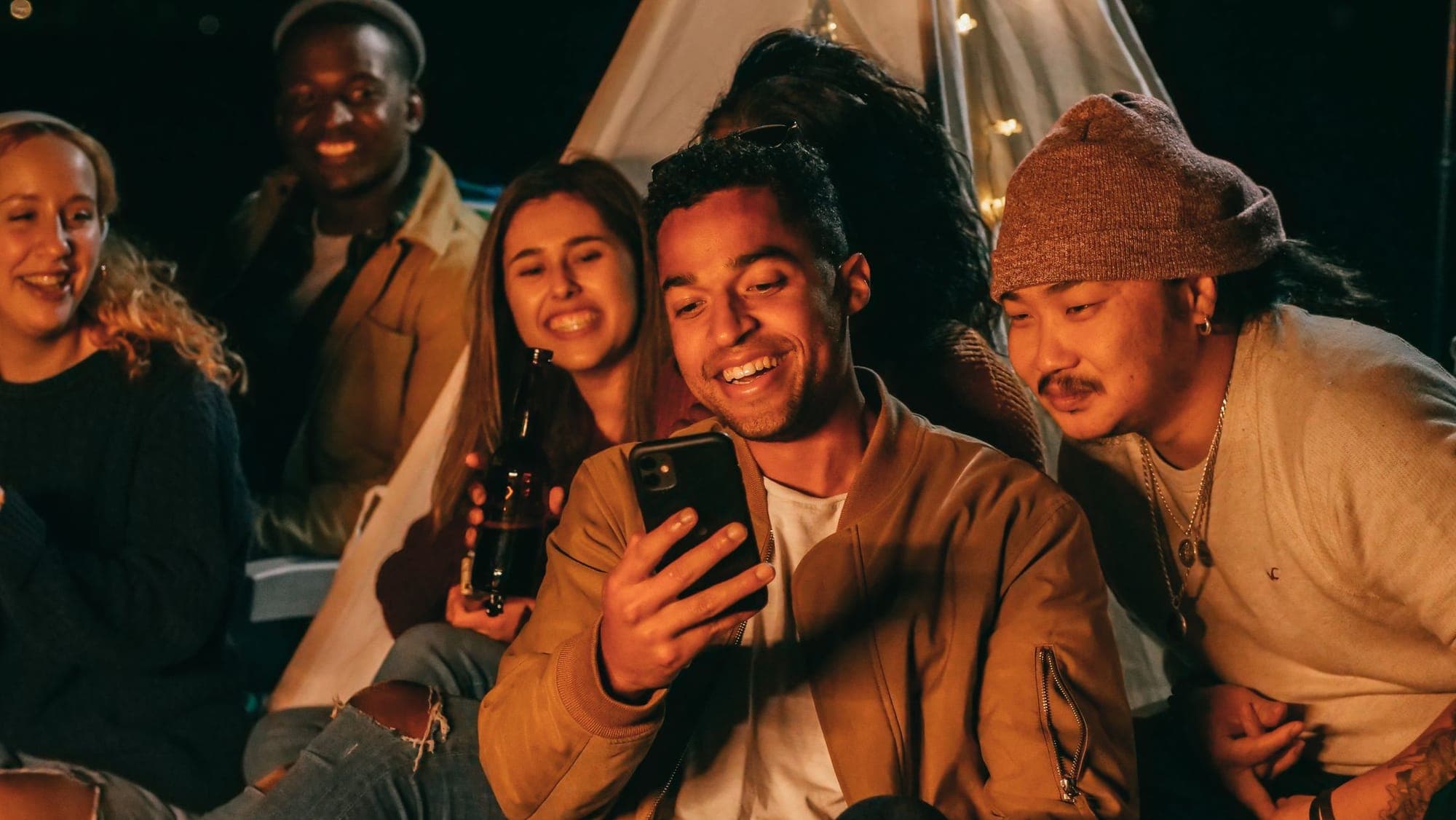 Friends gathered at night sharing something on a phone